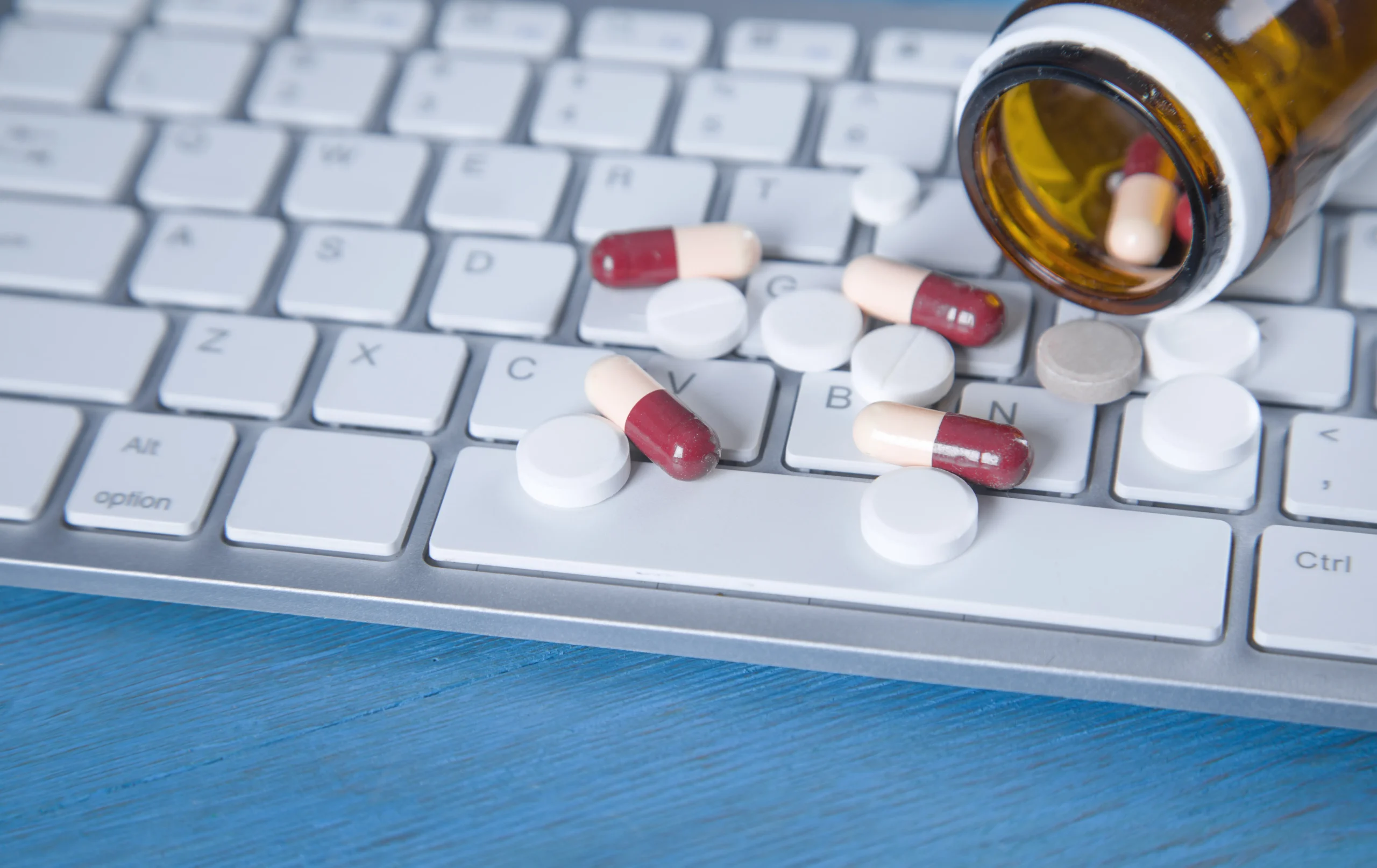 Laptop showing drug interaction data and clinical drug database icons.