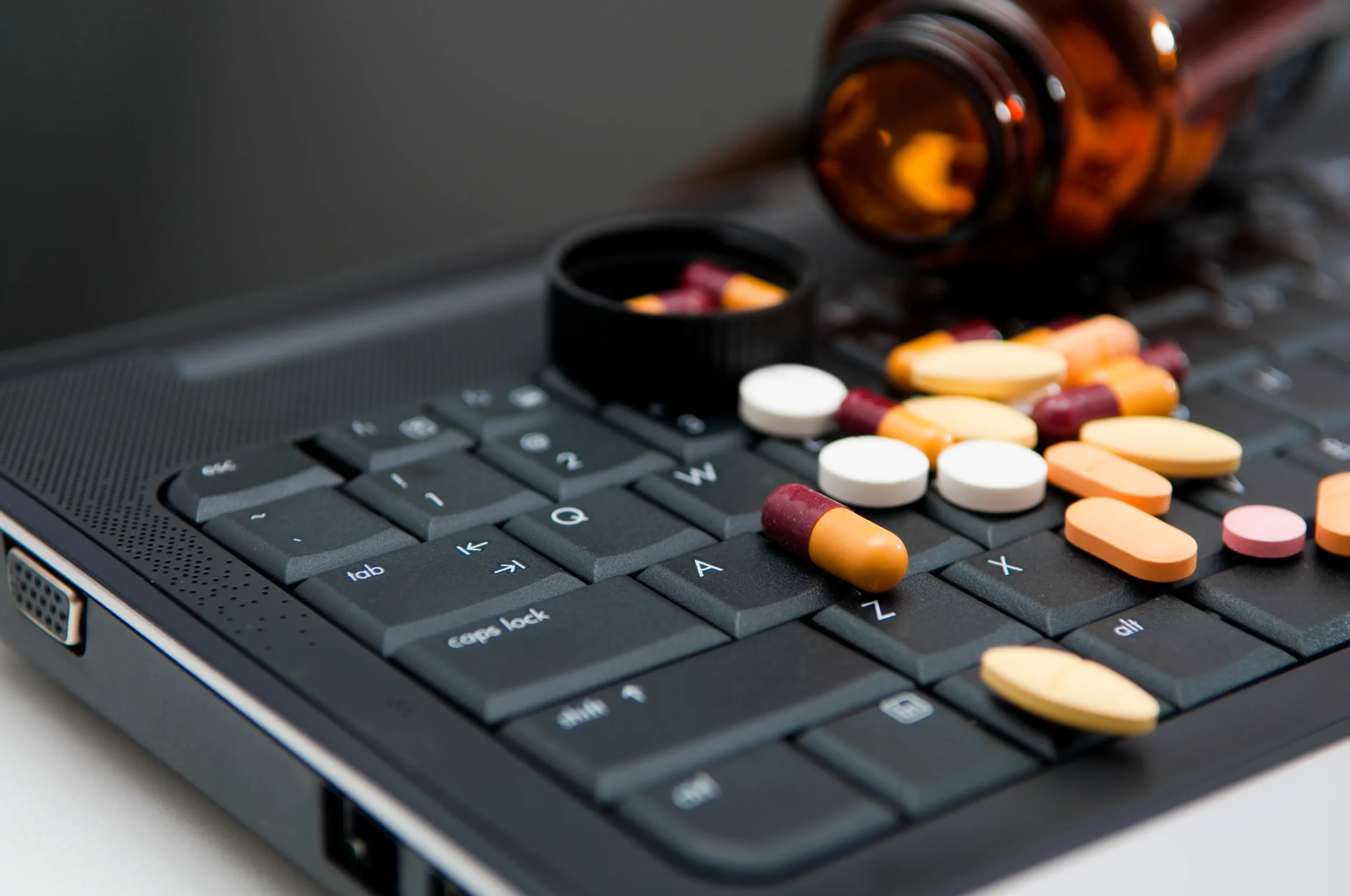 Pills on laptop for patient safety in healthcare, medication data management, EHR medication safety.