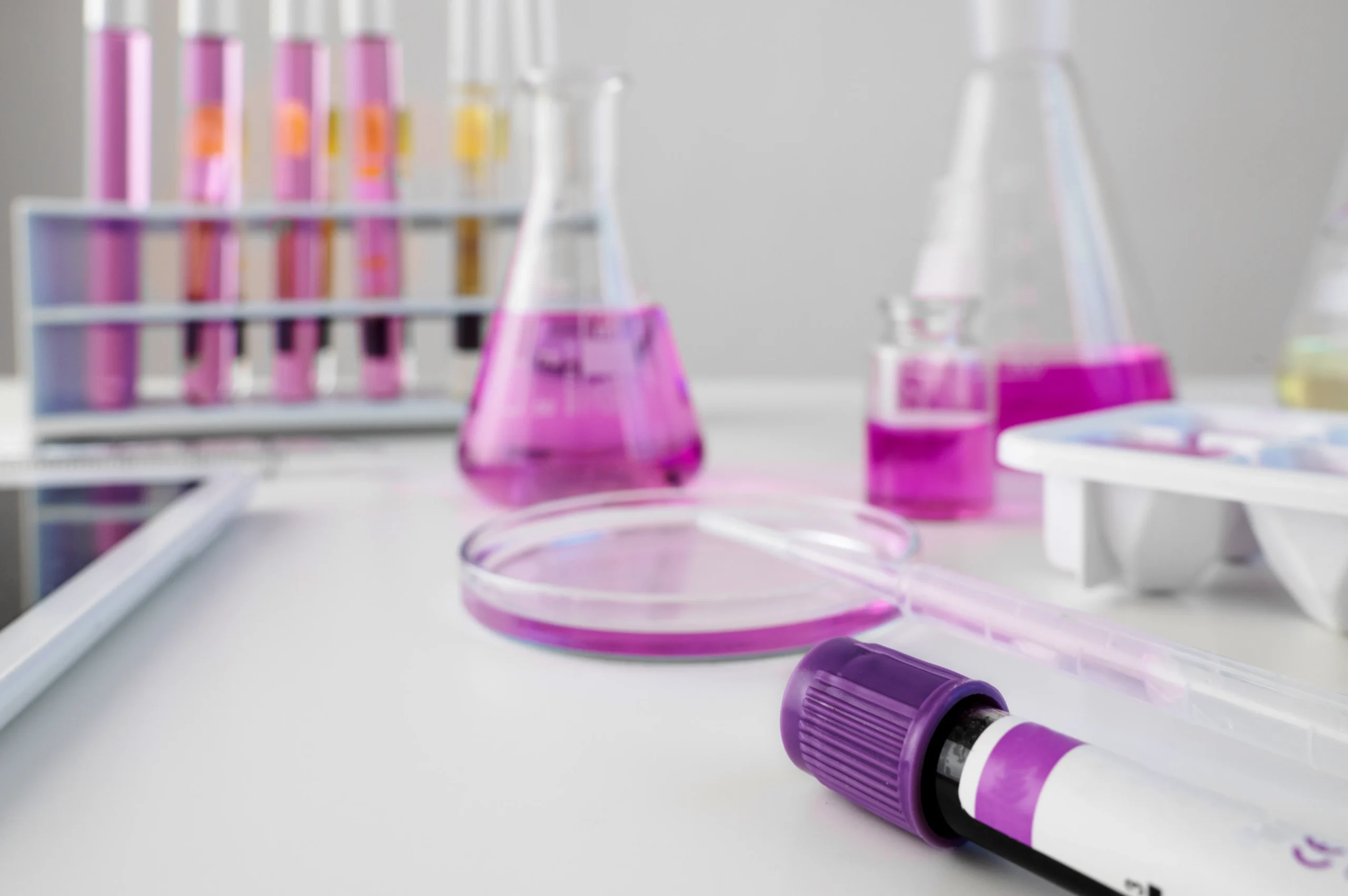 Lab flasks and test tubes holding purple solutions next to a tablet. This reflects how a drug data platform compiles vital drug target data.