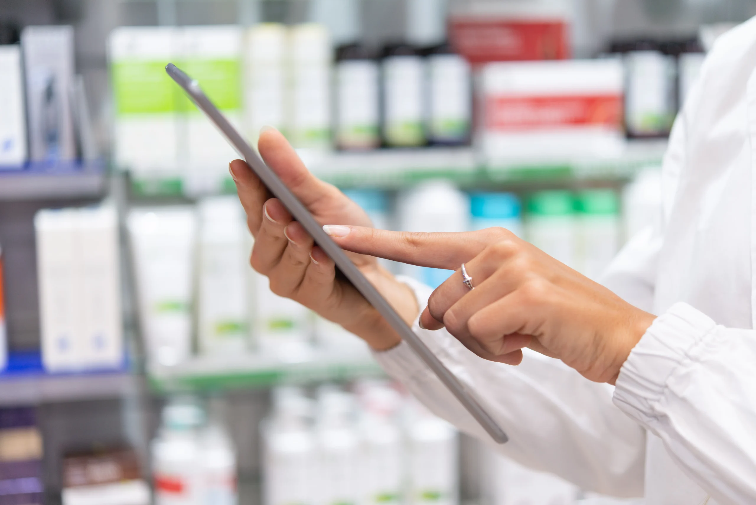 A healthcare professional using a tablet in a pharmacy to access vital metrics via a Drug Data API.