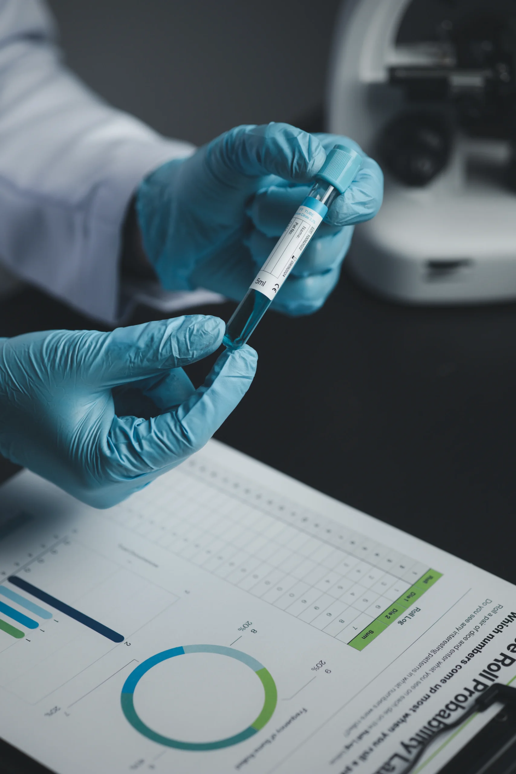 A researcher wearing blue gloves holding a chemical sample vial over a data sheet and pie chart, organizing raw information into structured clinical trial datasets.