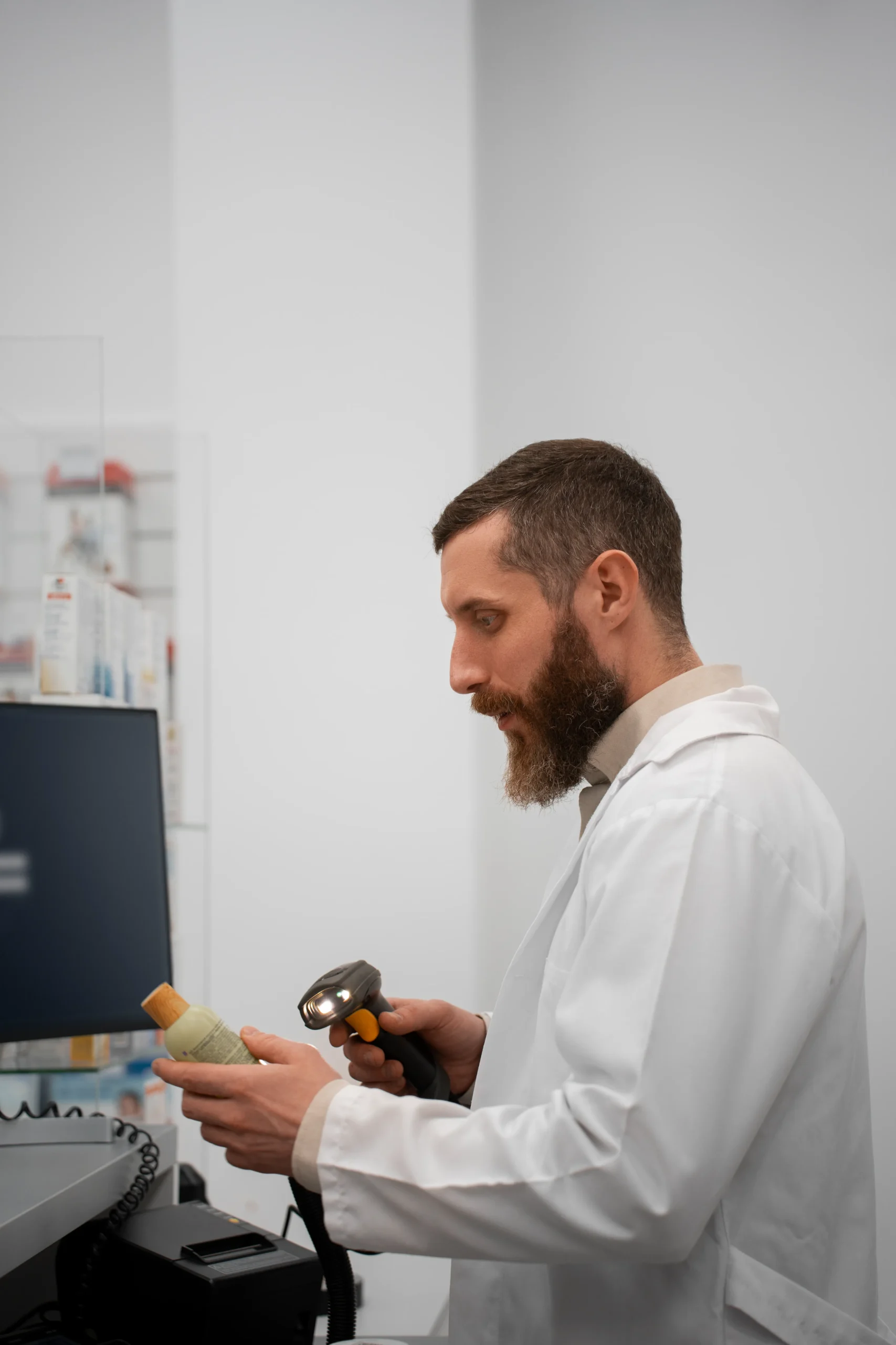 Pharmacist scanning medication barcodes into pharmacy management software at a checkout counter.